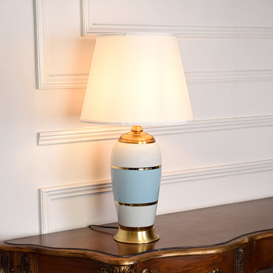Table lamp with white and light blue ceramic base and white fabric shade on wooden side table elegant lighting for living room decor.