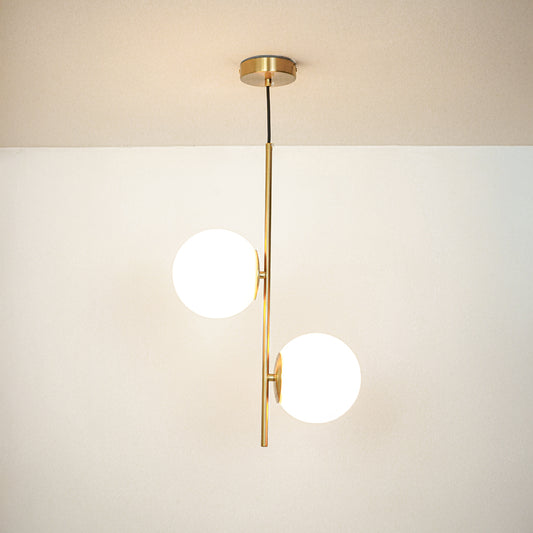 Gold pendant light with dual white glass globes on neutral background modern vertical lighting for living room and dining decor.