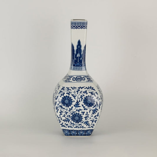 Blue and white ceramic jar with a tall narrow neck and intricate floral artwork shown in a studio setting creating a graceful artistic presence suited for elegant decor.