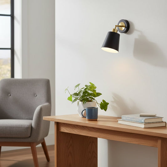 Modern black and gold metal wall light mounted above a wooden console adding warm ambient lighting to a stylish living room corner setting.