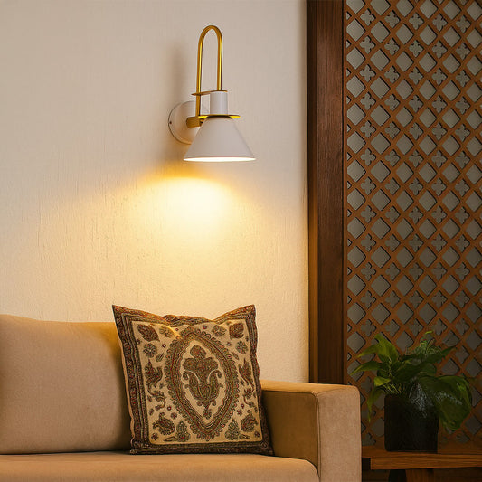 White and gold wall sconce glowing warmly beside bed adding modern elegance and charm to cozy home interiors.