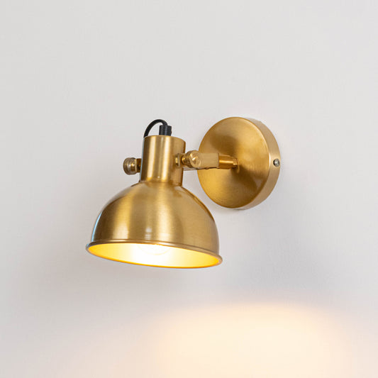 Industrial metal wall light in gold finish with dome shade for indoor or outdoor accent lighting decor placement white background.