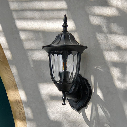 Black metal outdoor wall light lifestyle image with ribbed glass shade for elegant exterior entryway decor.