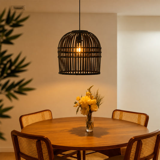 A black metal cage pendant light hangs above a round wooden dining table with four woven-back chairs. A glass vase with yellow flowers sits on the table, and warm sunlight streams in from the side against a beige wall.