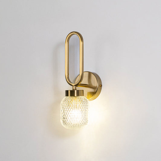 Modern wall light with gold metal frame and round glass bulb on neutral background minimal stylish lighting ideal for bedroom and living space decor.