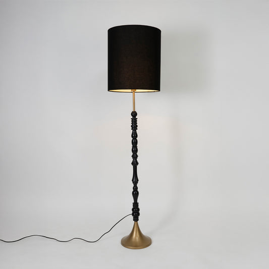 Black fabric shade floor lamp with turned wood stem and brass base designed for elegant living room and bedroom decor.