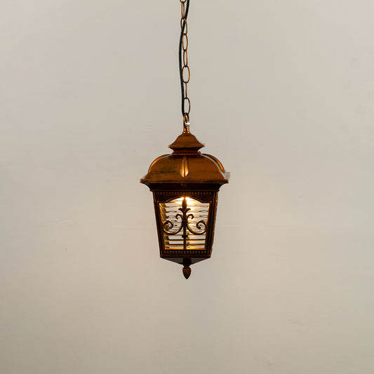 Copper metal hanging outdoor lantern with decorative glass panels glowing on white background ideal for porch entrance and exterior decor lighting.