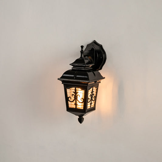 Black metal outdoor wall light on white background with an ornate lattice glass frame overlay for front porch decor.