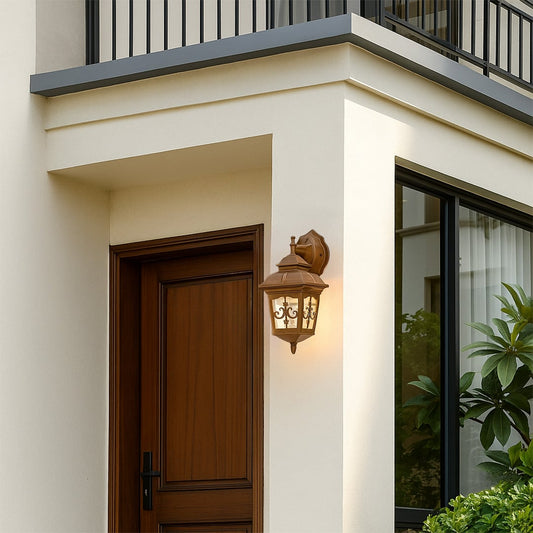 Gold outdoor wall lantern with decorative glass panels shown with the light on creating a warm welcoming glow beside the front door for elegant exterior styling.