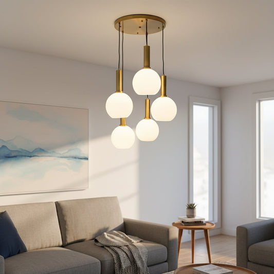 Modern five light pendant cluster with white globe shades and gold holders hanging from a round gold ceiling plate creating an elegant room look.