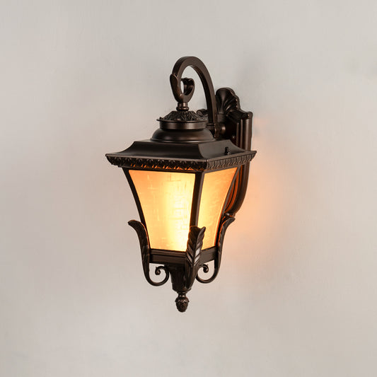 Antique bronze outdoor wall light on white background with an amber frosted glass shade for traditional porch decor.