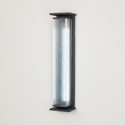 Black metal outdoor wall light on white background with ribbed glass shade for modern exterior decor.