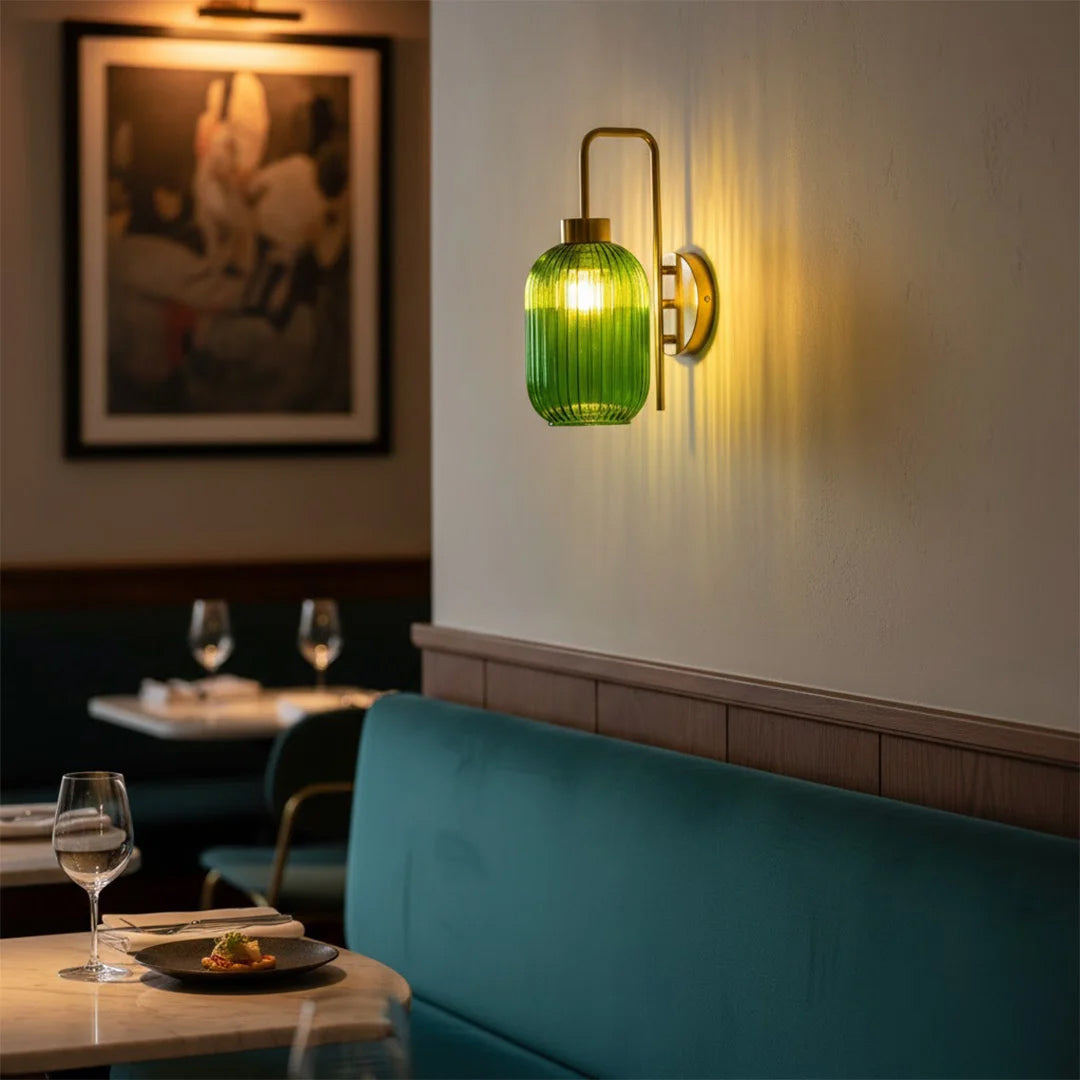 Gold wall light with green ribbed glass shade casting warm glow styled in modern interior setting for cozy wall decor ambiance.