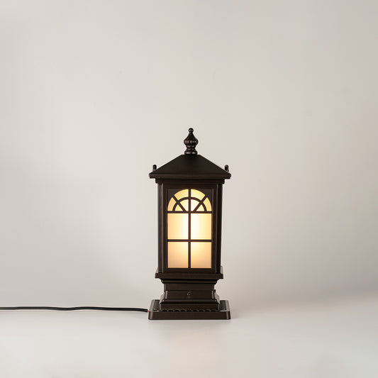 Vintage black outdoor gate light with warm glowing glass panels for elegant exterior decor use.