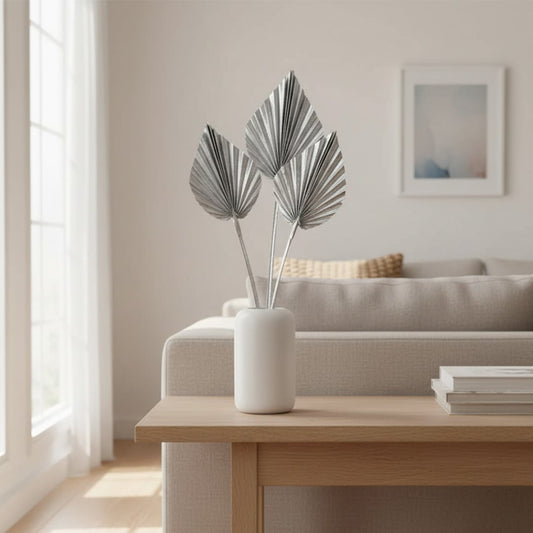 White ceramic vase with grey decorative leaves styled on table near sofa bringing calm neutral tones to modern home Decor.