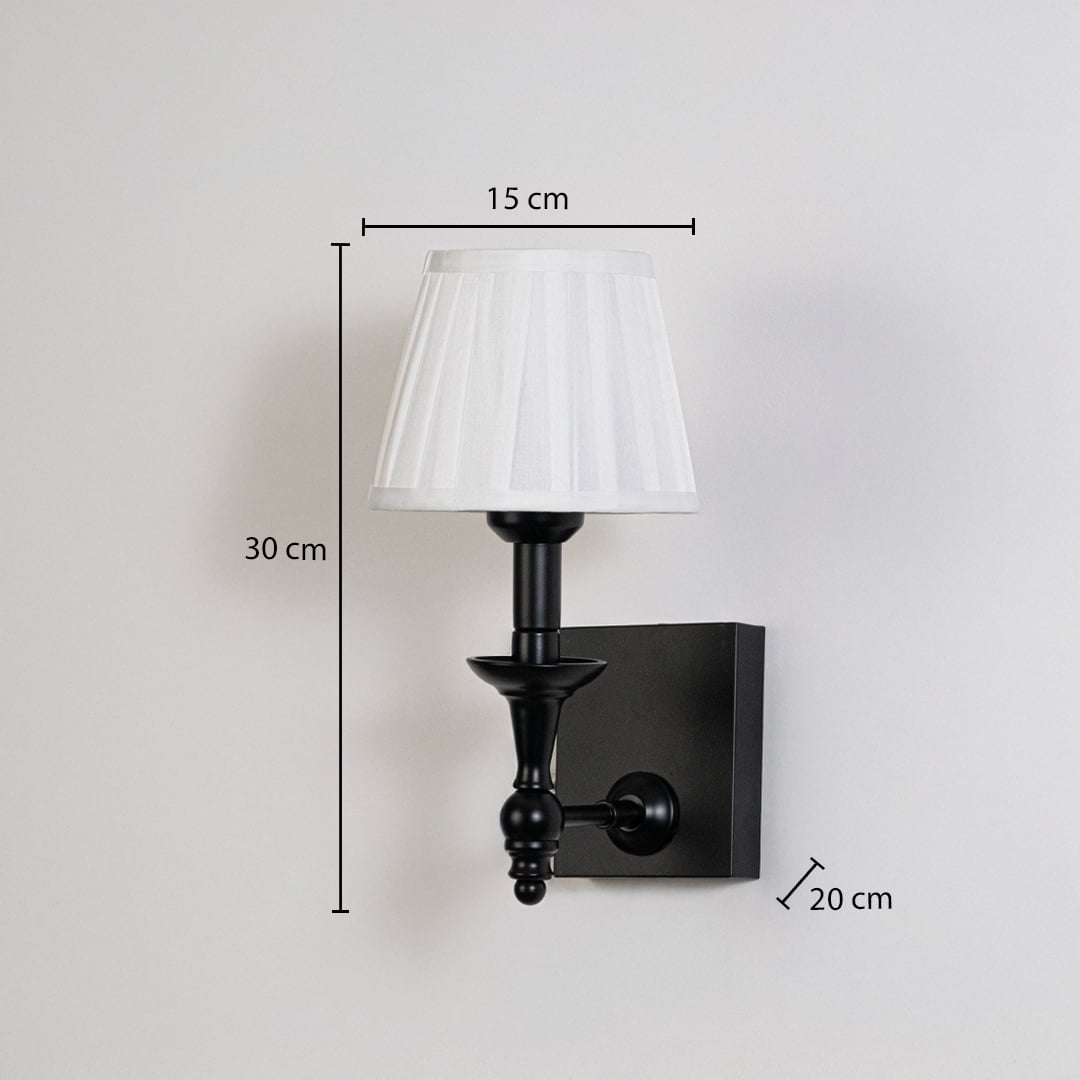 Black metal wall sconce with white pleated shade shown with 30 cm height and 15 cm width for precise size detail.