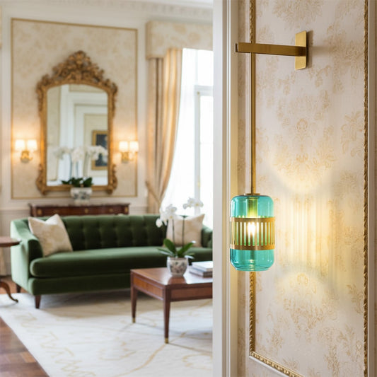 Wall light with metal arm and glass shade in gold and green mounted near mirror adding elegant accent lighting to living space.