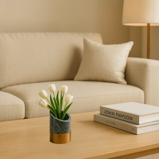 Minimal decorative planter with marble finish and brass base placed on wooden coffee table holding white flowers for modern living room decor.