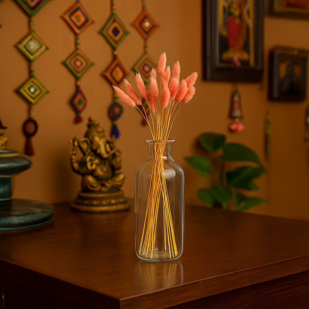Peach dried bunny tail grass arranged in a clear glass vase on a wooden table adding a warm artistic touch to a cozy traditional decor setting.