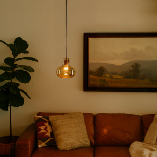 Modern amber glass pendant light with sleek golden finish placed in the living room to luxury home interiors.
