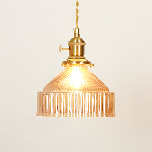 Amber ribbed glass pendant light with gold metal fixture illuminated to showcase elegant decorative ceiling lighting.