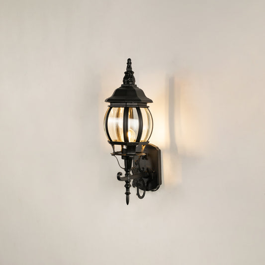 Black metal outdoor lantern wall light on white background with warm glow for elegant exterior decor.