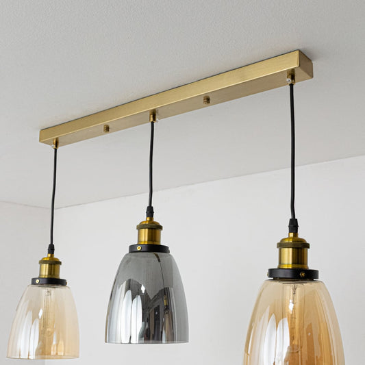 Close view of amber and smoked glass pendant shades showing their smooth reflective finish and gold detailing for stylish contemporary lighting.