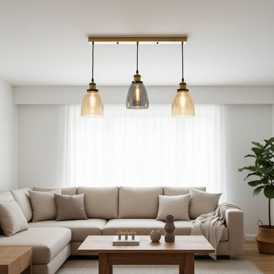 Modern glass pendant trio with amber and smoked shades and gold fittings hanging from a long gold bar creating a warm elegant accent in the room.