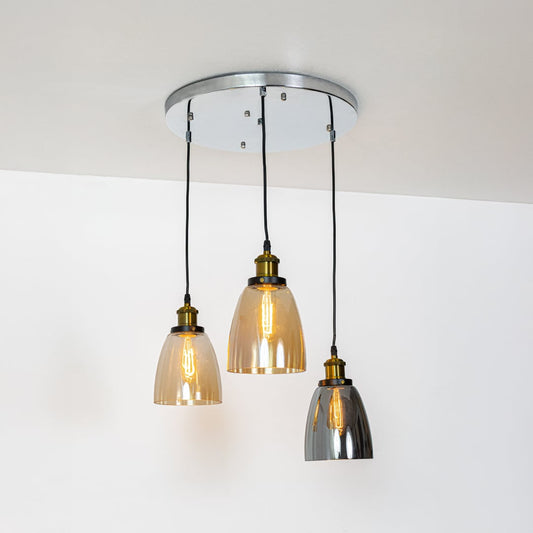 Warm glowing glass pendant lights with amber and smoked shades and gold accents displayed on a bright white background for decor inspiration.