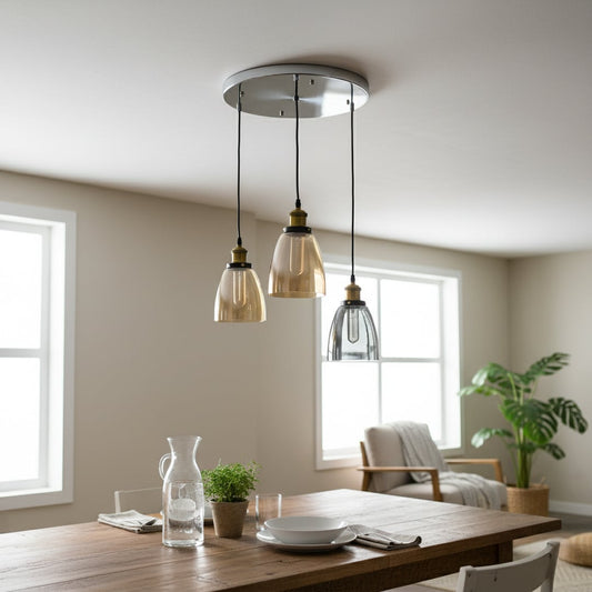 Modern glass pendant trio with amber and smoked shades and gold fittings hanging from a round silver plate creating a warm elegant focal point in the room.