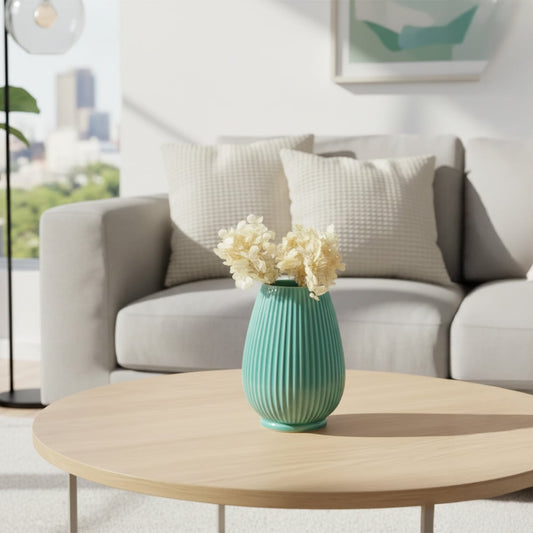 Green ceramic vase with dried florals placed on round wooden table creating fresh calming accent for modern living room Decor.