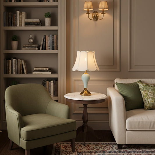 Table lamp with ceramic base and fabric shade placed between armchairs adding soft ambient lighting to elegant living room interior.