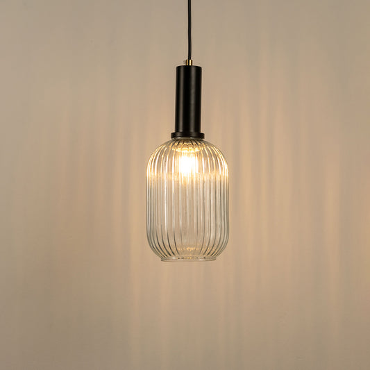 Clear ribbed glass pendant light with black holder and warm illumination on neutral background stylish modern hanging lighting for home decor.