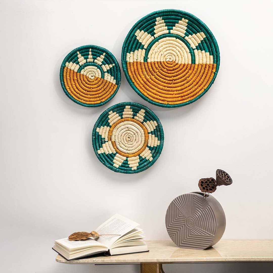 Woven seagrass wall basket set with teal sunrise pattern in lifestyle living room setting for boho home styling.