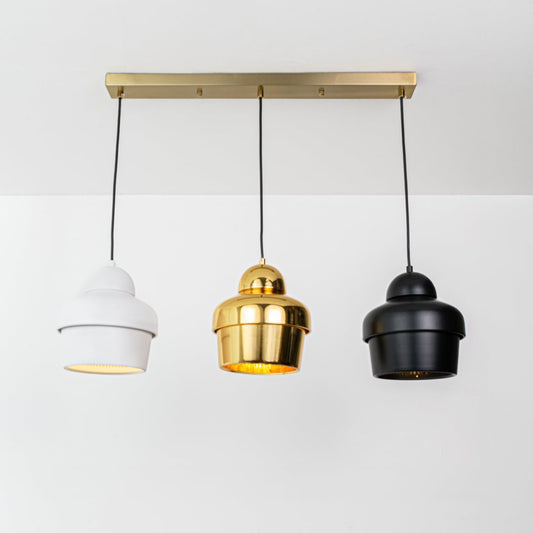 White gold and black pendant lights glowing softly on a white background creating warm ambient modern illumination.
