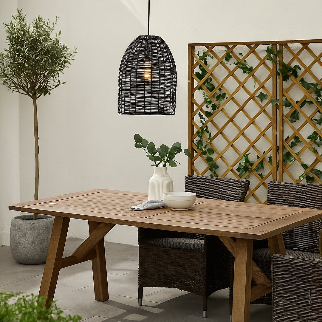 Black rattan pendant light with warm glow above outdoor dining table creating cozy modern patio decor ambiance.