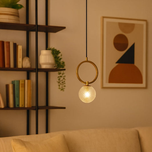 Gold ring pendant light with textured glass globe styled in a modern interior adding warm elegant illumination to home decor.