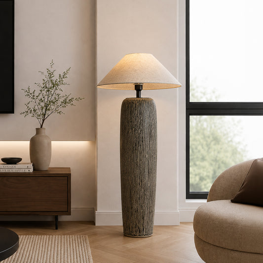 Modern grey textured ceramic tall floor lamp with a white shade illuminated beautifully in a minimalist living room corner.