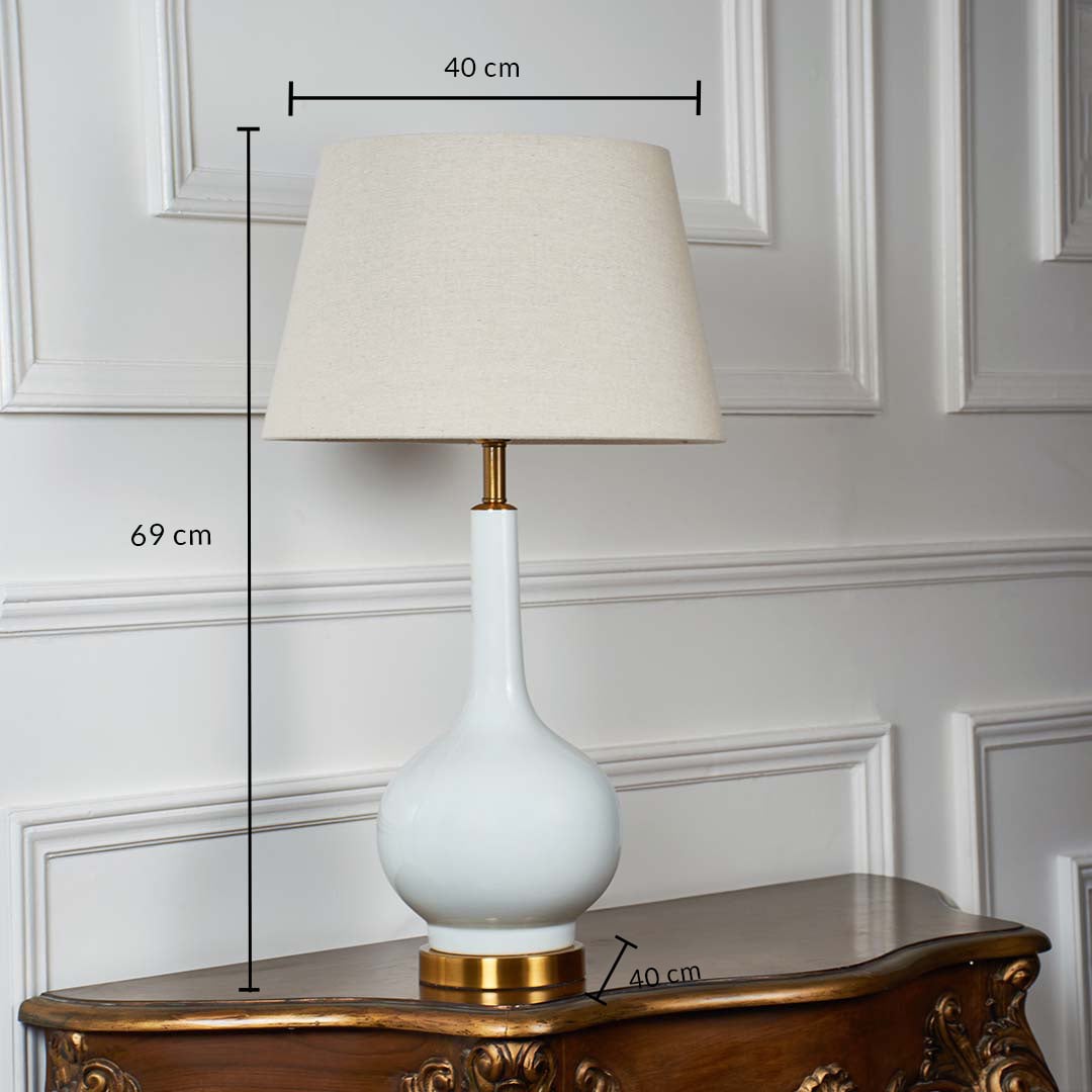 Ceramic table lamp dimensions — 69 cm tall and 40 cm wide — with beige shade and gold base displayed against white paneled background.