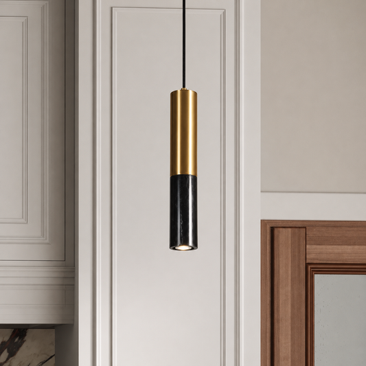 A modern cylindrical pendant light hanging in a doorway, featuring a brushed gold upper cylinder and a black lower cylinder, suspended by a thin black cord.