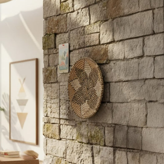Handcrafted round wall decor in natural fiber finish mounted on stone wall adding earthy texture and warm accent to modern living space.