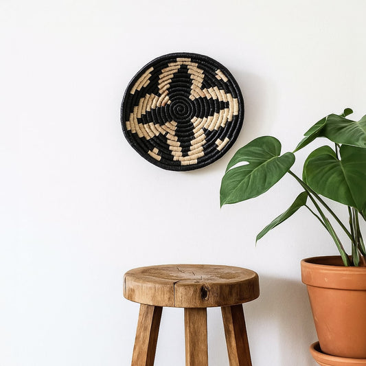 Round metal wall decor with abstract tribal inspired pattern displayed above wooden stool adding artistic contrast and handcrafted charm to modern interiors.