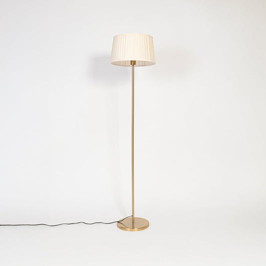 Floor lamp with white pleated fabric shade and golden stand displayed on white background with light off.