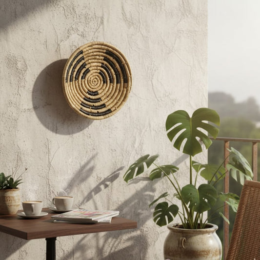 Handwoven round wall basket Decor displayed on a textured balcony wall with indoor plants wooden table coffee cups and soft sunlight creating a calm boho lifestyle setting.