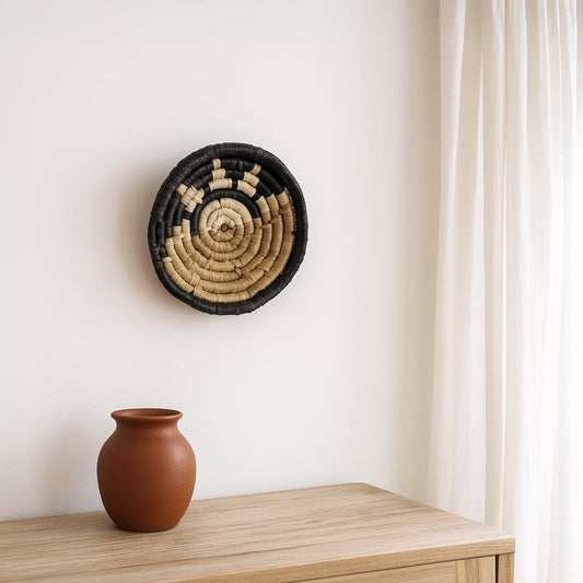 Decorative round wall clock with botanical leaf design in earthy finish displayed on shelf creating warm handcrafted appeal for modern home decor styling.