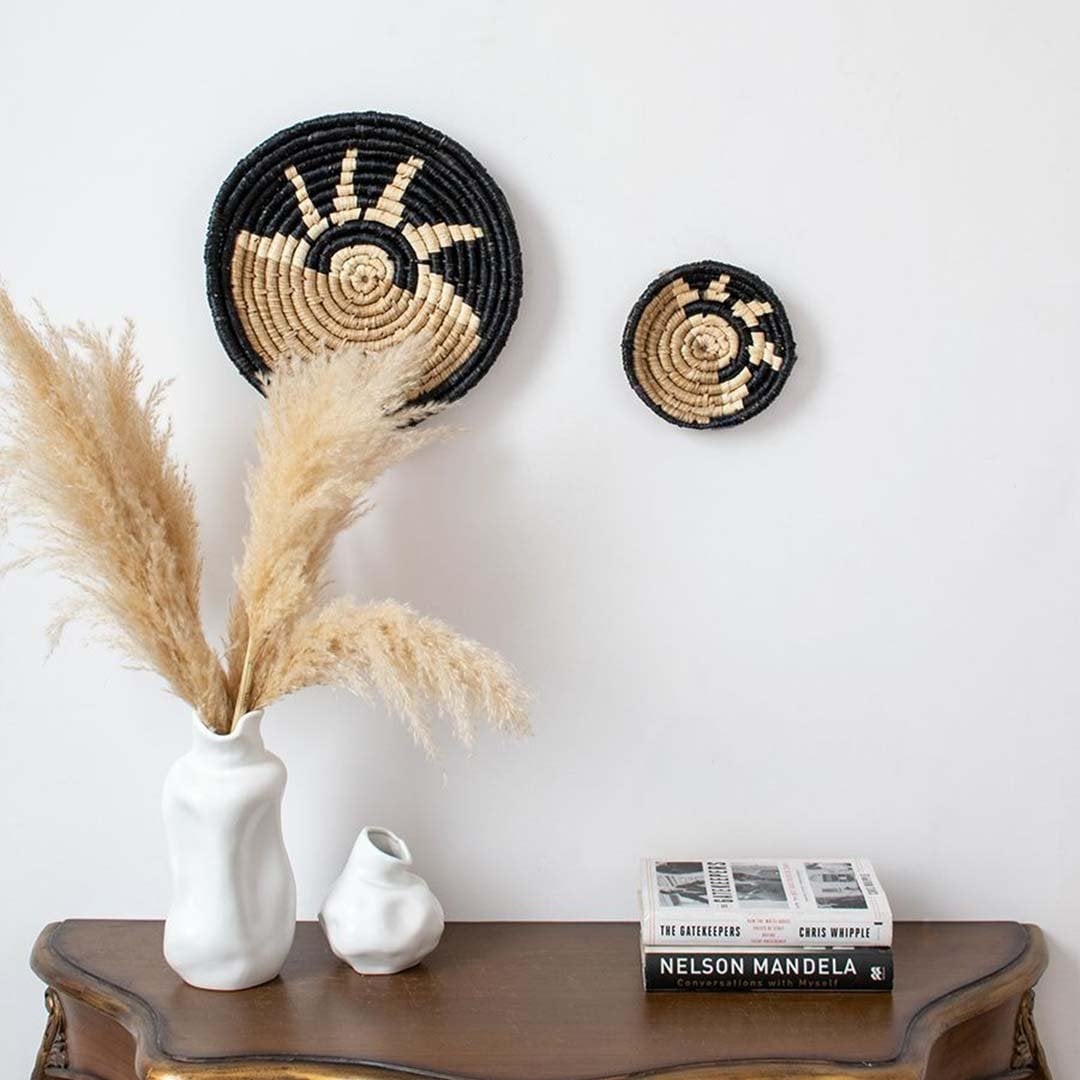 Bamboo wall plates in black beige tones styled with pampas grass vase adding warm natural texture to home decor.