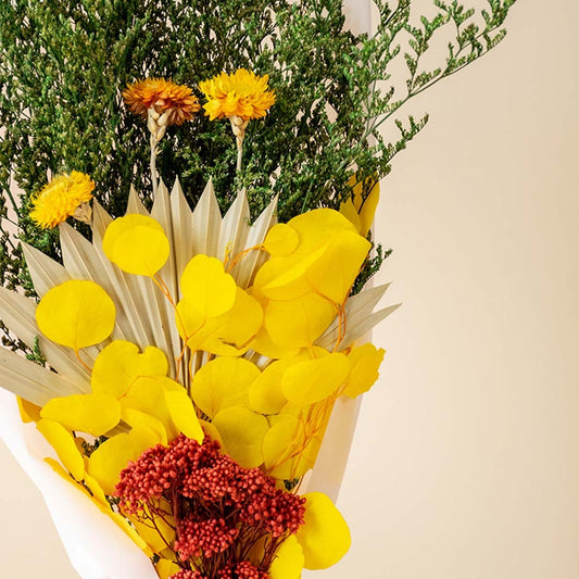 Closeup view of yellow and green preserved dried flower bouquet showing layered textures natural stems and handcrafted floral detailing.