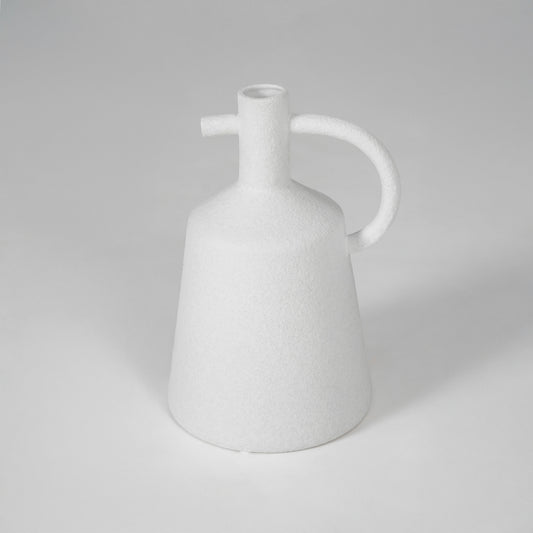 White ceramic vase with curved handle for modern shelf placement and elegant indoor decor styling accent piece.