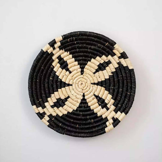 Handwoven seagrass round wall basket decor in black and natural beige with floral woven pattern displayed on white background.