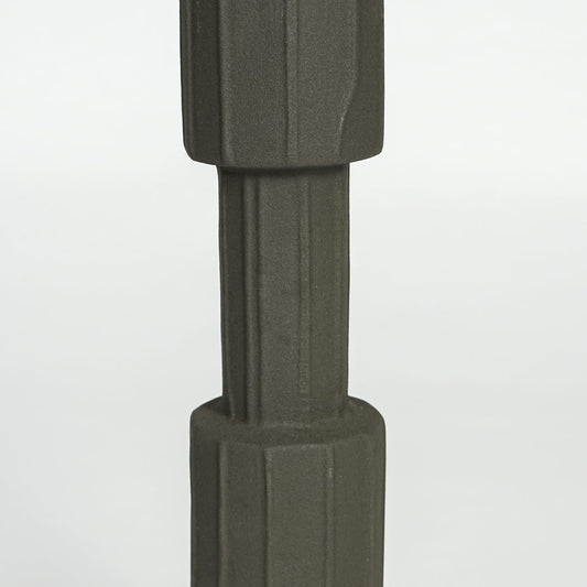 Close view of dark green metal candle holder highlighting faceted cylindrical design and matte textured finish.